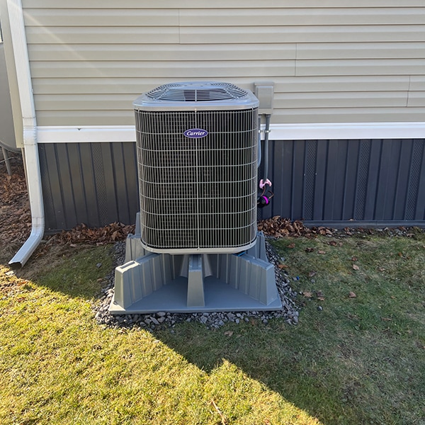 Carrier Heat Pump Installation in Loretto, PA 15940 along the site of a beige house with green grass.