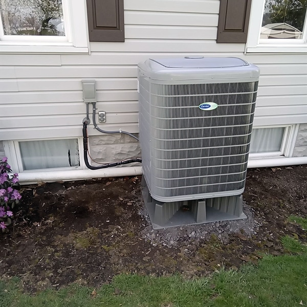 Carrier Heat Pump Installation in Martinsburg, PA 16662 with purple flowers to the right of the system.