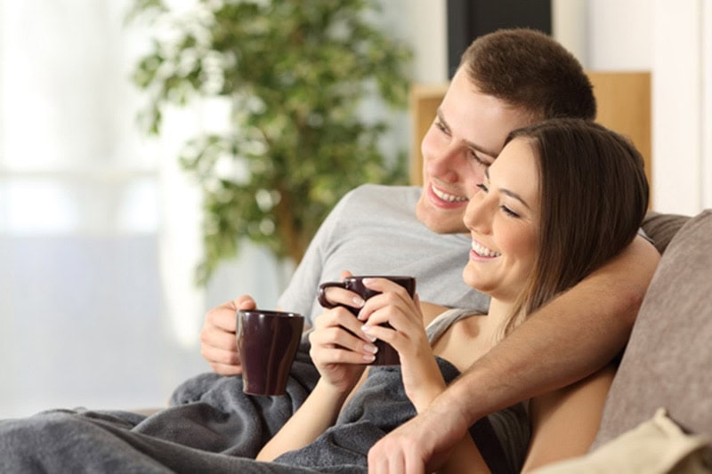 happy couple drinking coffee on the couch