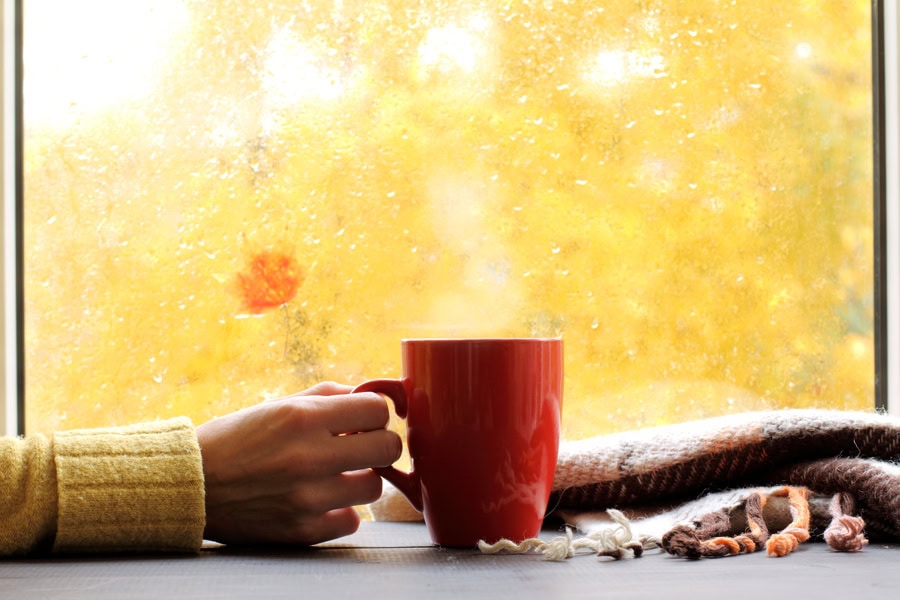 red mug of hot drink, when behind a window is rain in autumn in Altoona, PA