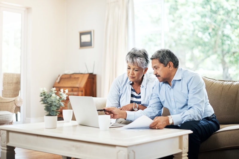 What Do Air Purifiers and Air Filters Do? Photo of senior couple sitting in their living room together on a laptop.