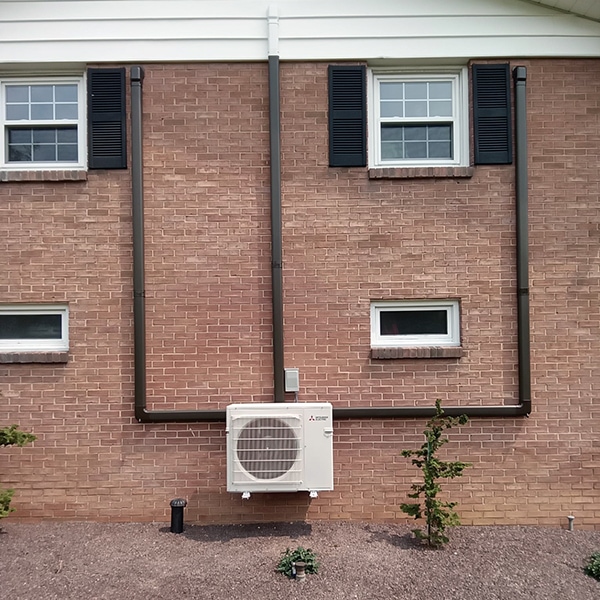 Mitsubishi Ductless Mini Split Installation in Martinsburg, PA 16662 - outdoor unit installed against a red brick house.