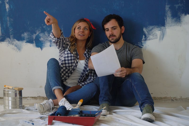 Couple sitting on floor discussing plans to paint home.